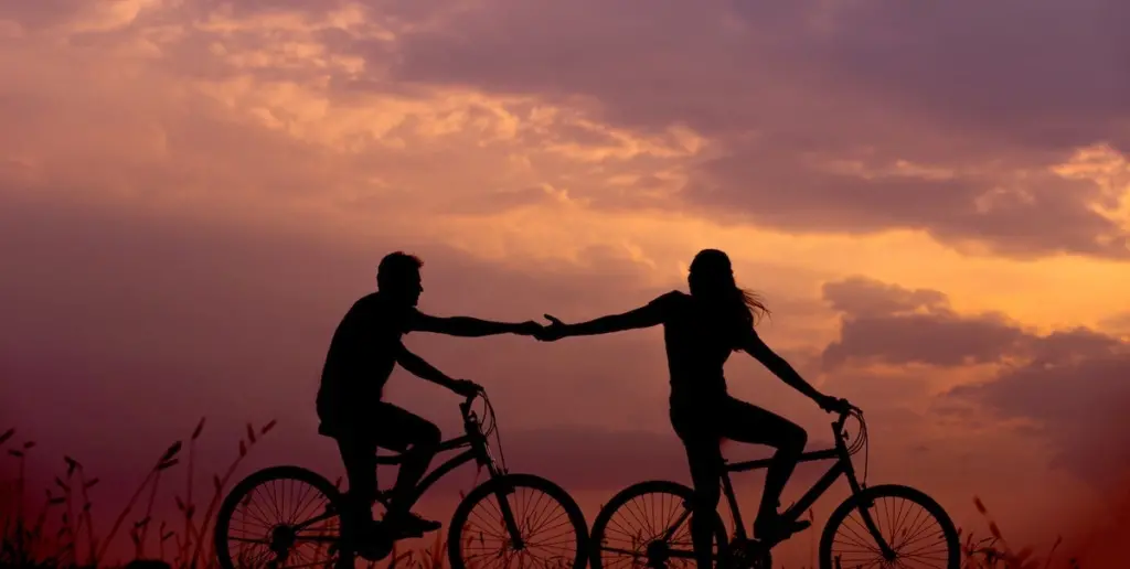 couple-bicycling-holding-hands