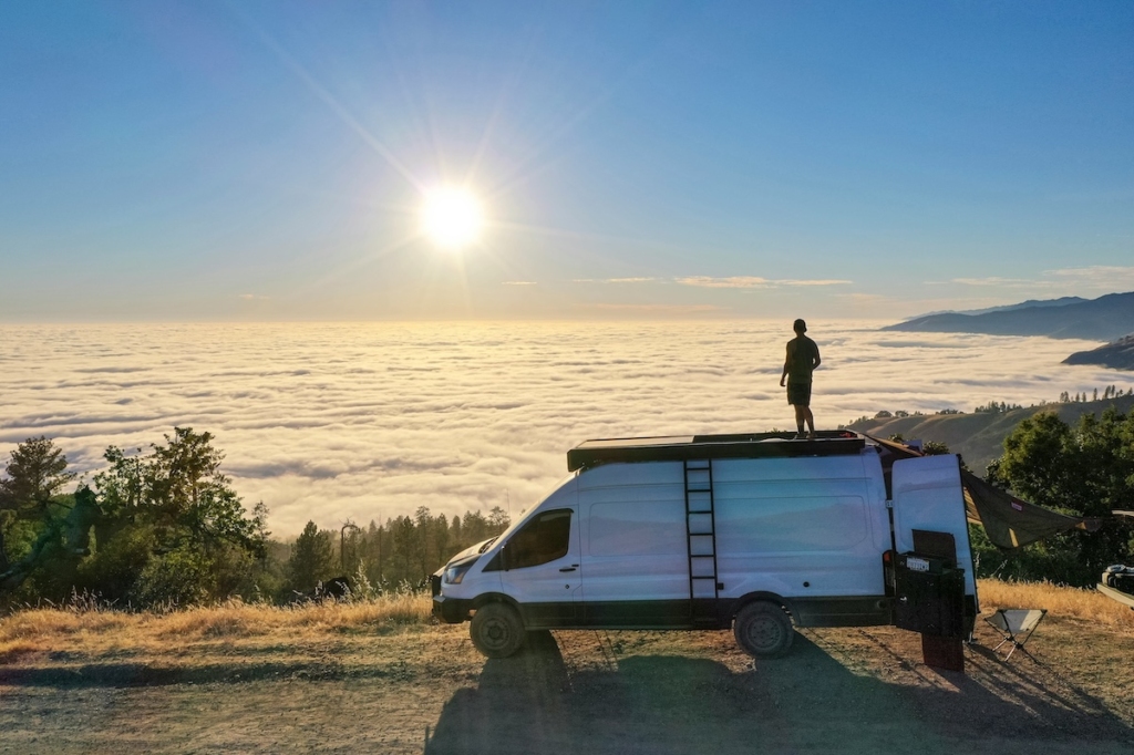 man-standing-on-sprinter-van-looking-at-sunset